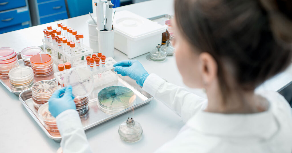 A pathologist looking at tissue sample on petri dish in a laboratory.